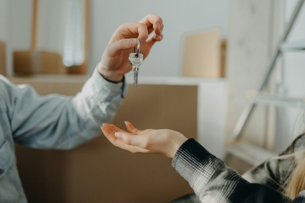 Someone dropping a house key into the open palm of the new homeowner, for “What are the Best Investments for Millenials?”