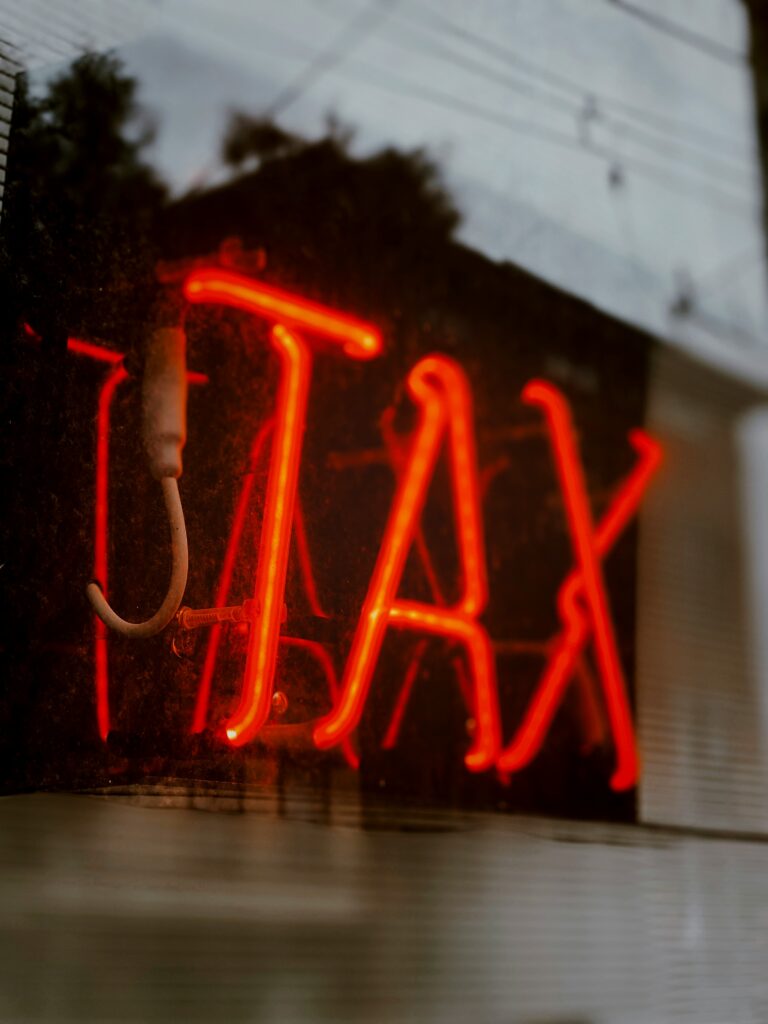 A red neon sign reading TAX, for “Building a Tax-Efficient Portfolio: Tips for Accredited Investors Looking Beyond Stocks and Bonds”