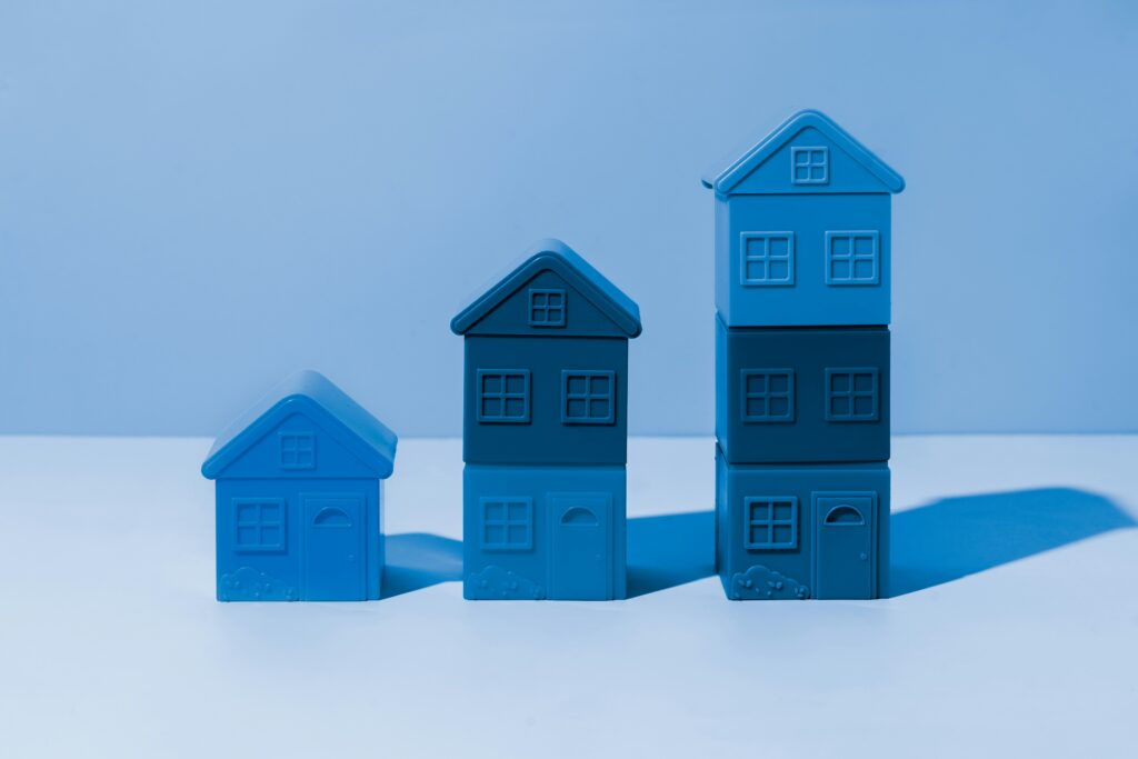 Three increasingly large blue houses lined up next to each other, for “Building a Tax-Efficient Portfolio: Tips for Accredited Investors Looking Beyond Stocks and Bonds”