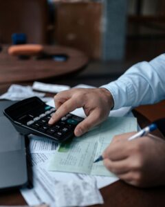 Someone using a calculator to fill in tax forms, for "How Tax-Efficient Is Your Portfolio? Take our Quiz"