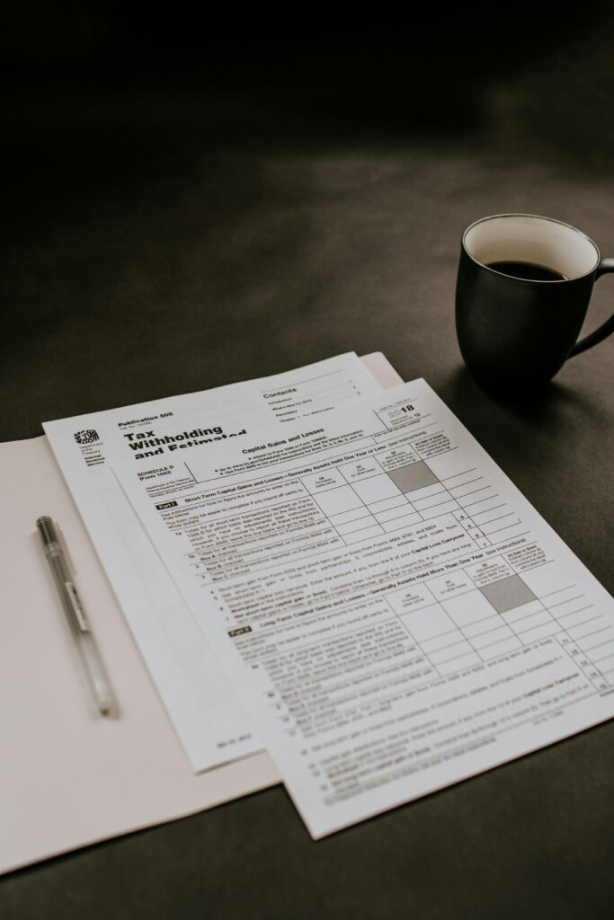 Interior, tax forms spread out on a table with a cup of coffee, for "Quiz! Which Tax Strategies Could Work for Your Alternative Asset Portfolio?"